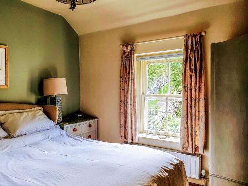 a bedroom with a bed and a window at Penny Cottage in Bonsall