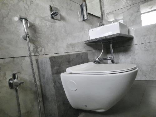 uma casa de banho com um WC com um lavatório e um espelho em Raapan Beach Resort em Malvan
