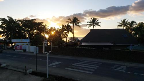 a sunset over a street with palm trees and a building at Moorea Maharepa Appartement in Paraoro
