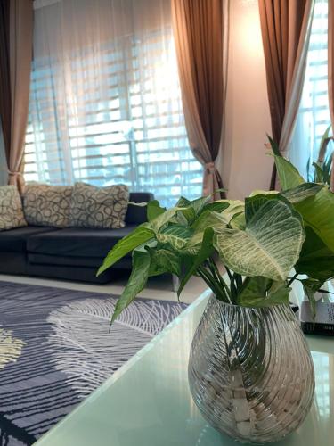 a vase with a plant sitting on a table in a living room at Homestay Aalaiya Bertam Kepala Batas - Fully Aircond in Kepala Batas