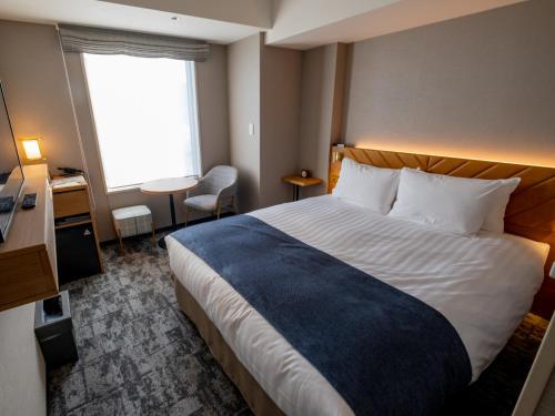 a hotel room with a bed and a desk and a window at Tokyu Stay Hakodate Asaichi Akarinoyu in Hakodate