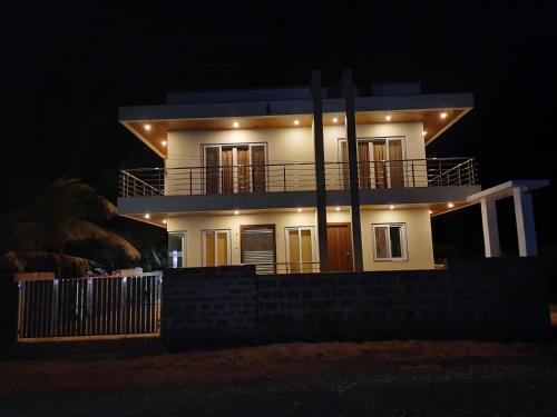 a white house with a balcony at night at Raapan Beach Resort in Malvan