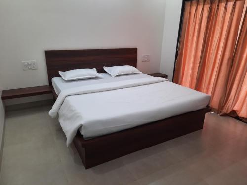 a bedroom with two beds and an orange curtain at Raapan Beach Resort in Malvan
