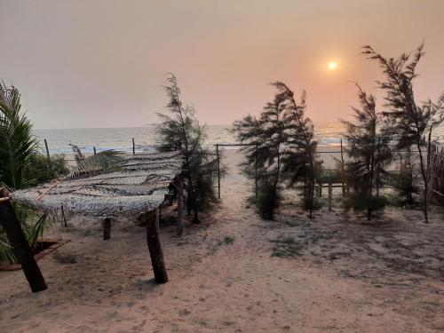 a bench on the beach with the sunset in the background at Raapan Beach Resort in Malvan