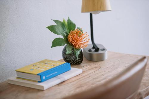 a table with books and a vase with an orange flower at SCP Hilo Hotel in Hilo