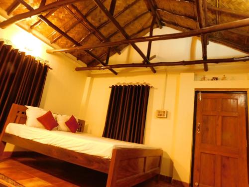 een slaapkamer met een houten bed en een houten deur bij Gram Bangla Retreat in Calcutta