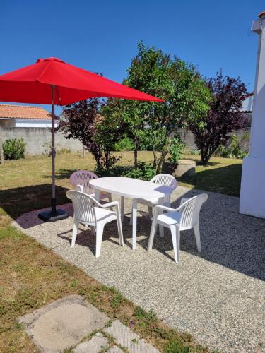 a white table and chairs with a red umbrella at EOLE - Maison Saint Jean de Monts - 2 pièces - 4 personnes in Saint-Jean-de-Monts