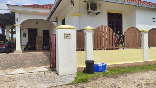 a white and yellow house with a gate and a fence at Room 345 in Kota Bharu