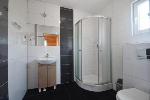 a white bathroom with a sink and a shower at Stecyk - Domki nad morzem, Trzęsacz in Trzęsacz