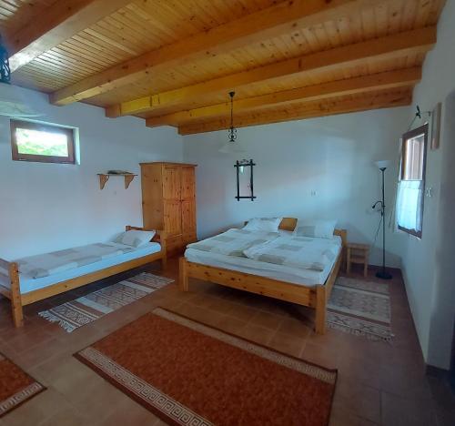 a bedroom with two beds and a wooden ceiling at Szenkeparti Vendégház in Penyige