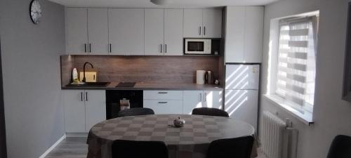 una cocina con mesa con sillas y una cocina con armarios blancos. en Apartament u Marzenki, en Augustów