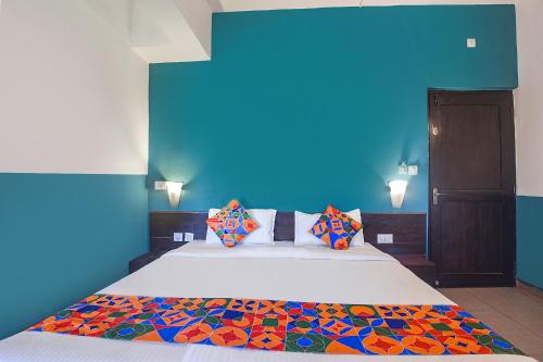 a bedroom with a large bed with a blue wall at FabExpress Paradise Inn Panaji in Old Goa