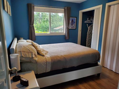 a bedroom with blue walls and a bed with a window at Saratoga beach cottage, private non-resort, easy beach access, 35mins Mt Washington in Oyster Bay