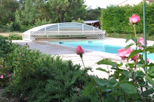 une piscine avec un pont dans un jardin dans l'établissement la ferme de tonton Jules 1, à Entraigues-sur-la-Sorgue