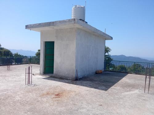 a small building with a green door and a fence at Travelodge Homestay in Bīr