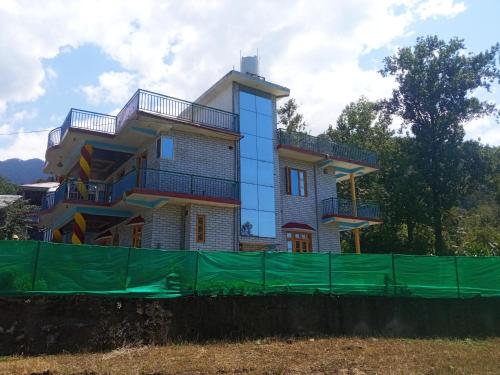a house with a green fence in front of it at Travelodge Homestay in Bīr