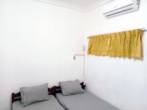 a room with a bed and a yellow curtain at Moshi Moshi in Probolinggo