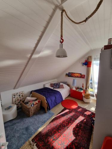 - une chambre mansardée avec un lit et un tapis dans l'établissement Maison bord de mer, à Zuydcoote