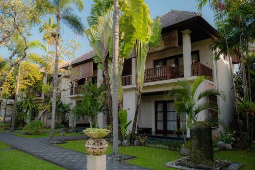 a house with palm trees in front of it at Griya Santrian a Beach Resort And Spa in Sanur