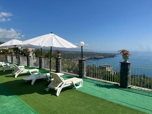 a group of chairs and umbrellas on a balcony with the ocean at Tenuta la Timpa Vela rooms And pool in Acireale