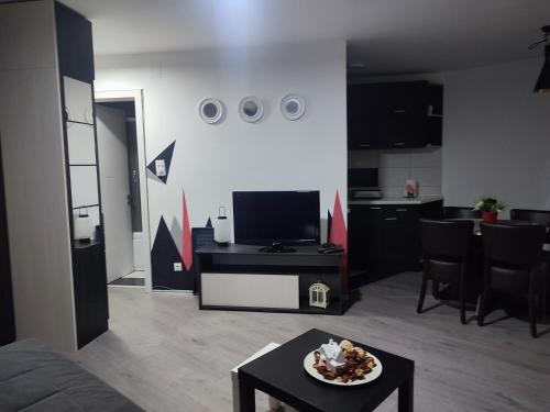 uma sala de estar com televisão e uma mesa com um prato de comida em Triangle studio 4 Divcibare em Divčibare