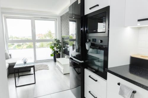 a kitchen with a black refrigerator and a table at Chill Apartments Jurajska Plaza Kielce Targi in Kielce