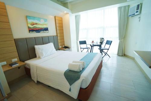 Un dormitorio con una cama grande y una mesa con sillas. en Chambre Hotel Mactan en Isla de Mactán
