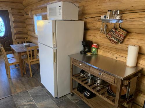 cocina con nevera blanca y mesa en The Chena Valley Cabin, perfect for aurora viewing, en Pleasant Valley