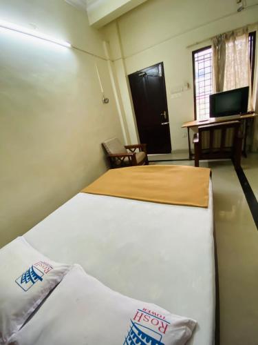 a bedroom with a bed and a desk and a television at Rosh Tower in Trivandrum