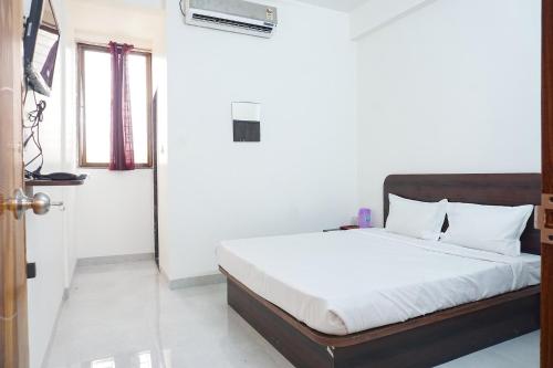 a bedroom with a bed with white sheets at FabExpress Gargi Galuxe - Nr Ankushrao Natyagruha in Pune