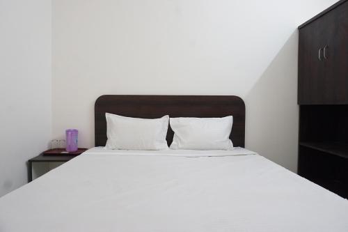 a bedroom with a large white bed with a wooden headboard at FabExpress Gargi Galuxe - Nr Ankushrao Natyagruha in Pune