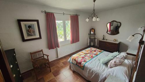 ein Schlafzimmer mit einem Bett, einem Stuhl und einem Fenster in der Unterkunft El huerto de la Reina in Becerril de la Sierra
