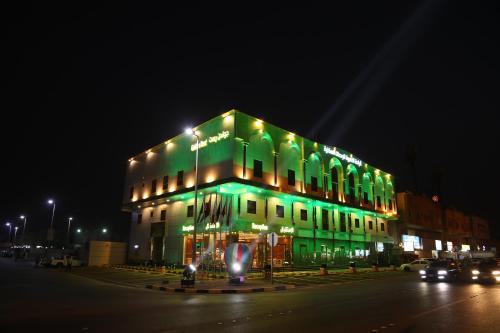 a green building with lights on it at night at Golden Rest Serviced Apartments in Al Khobar
