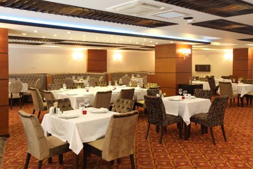 uma sala de jantar com mesas e cadeiras brancas em Arya Hotel Sakarya em Sakarya
