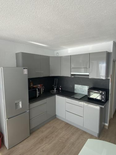  La cuisine est équipée de placards blancs et d'un réfrigérateur. dans l'établissement Appartement à 2 min du port, à Saint-Cyprien