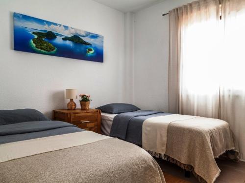 a bedroom with two beds and a painting on the wall at BLUE WATERS Apartment with heated pool in Costa Del Silencio