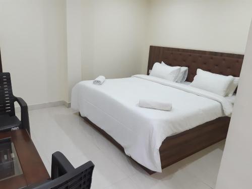 Un dormitorio con una cama grande con sábanas blancas. en CNR Residency, Madanapalle, en Madanapalle