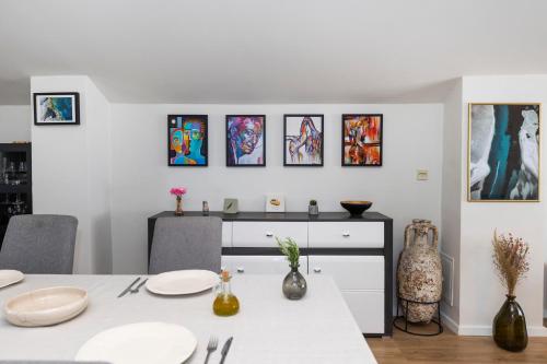 a dining room with a white table and some paintings at Sunset Apartment in Zadar