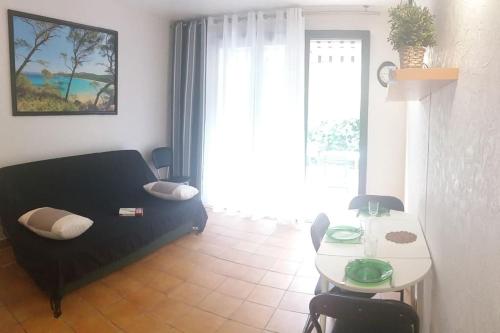 sala de estar con sofá negro y mesa en T1 rez de jardin avec grande terrasse – St Aygulf, en Fréjus