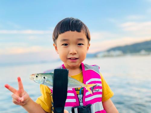 Ein kleiner Junge, der einen Fisch am Strand hält. in der Unterkunft Awakan in Sumoto