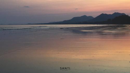 a beach at sunset with mountains in the background at SANTI beach retreat in Ban Rang Pla