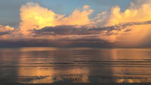 a sunset over the ocean with the words sanditt at SANTI beach retreat in Ban Rang Pla