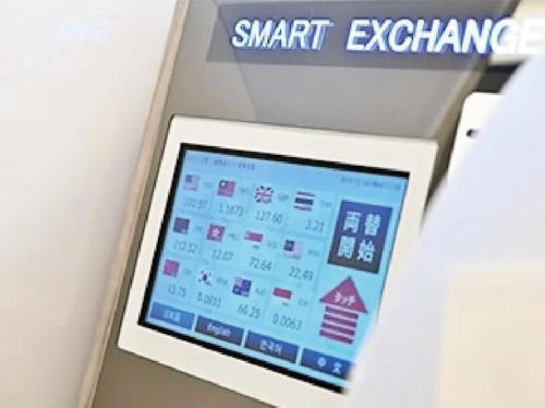 an electronic machine with a smart exchange sign on a wall at Odysis Suites Osaka Airport Hotel in Izumi-Sano