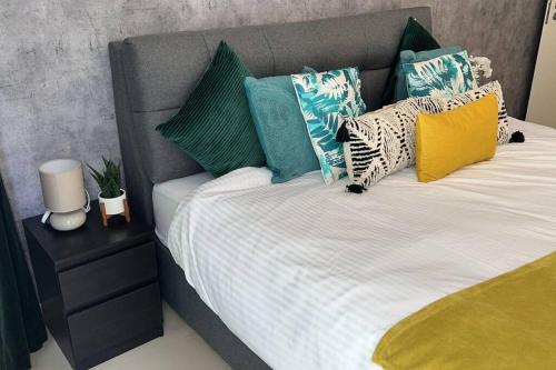 a bed with colorful pillows on top of it at Beach Dream - a luxury 1 bedroom apartment with direct beach access in Ras al Khaimah