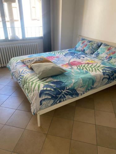 a bed with a colorful comforter and a pillow on it at Civico 18 B&B in Montecchio Emilia