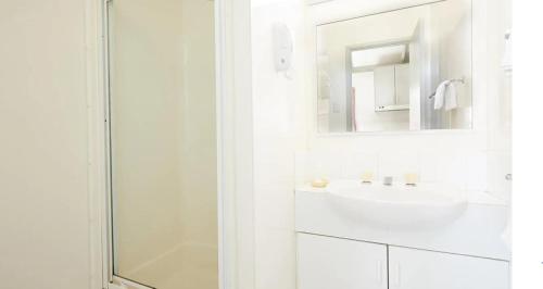 a white bathroom with a sink and a mirror at Apex RiverBeach Holiday Park in Mildura