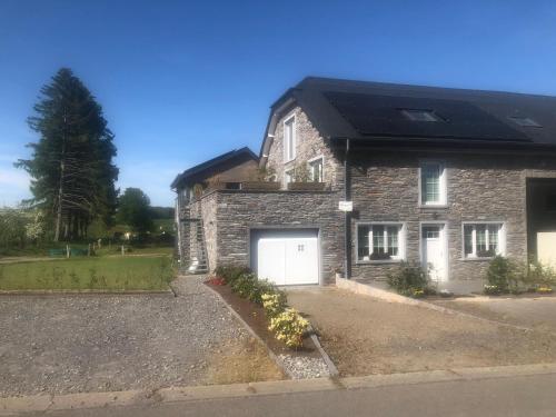 a brick house with a garage and a solar roof at PEGASUS I - 2 chambres de luxe, cuisine, salon, 2 terrasses et sauna in Vielsalm
