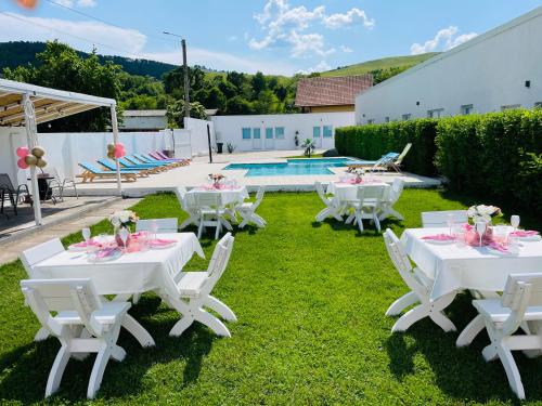 um grupo de mesas e cadeiras na relva junto a uma piscina em Blue Sky Transalpina em Săsciori