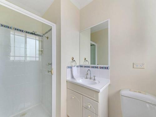 a white bathroom with a sink and a mirror at Spacious Home in West Moonah, Hobart in Moonah