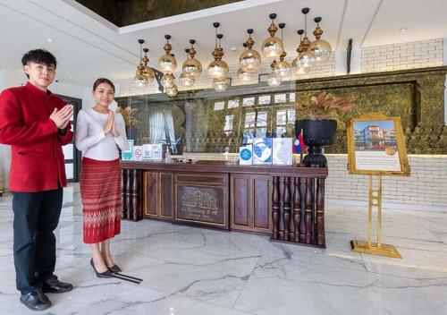 a man and a woman standing in front of a counter at Le Thatluang D'oR Boutique Hotel in Vientiane